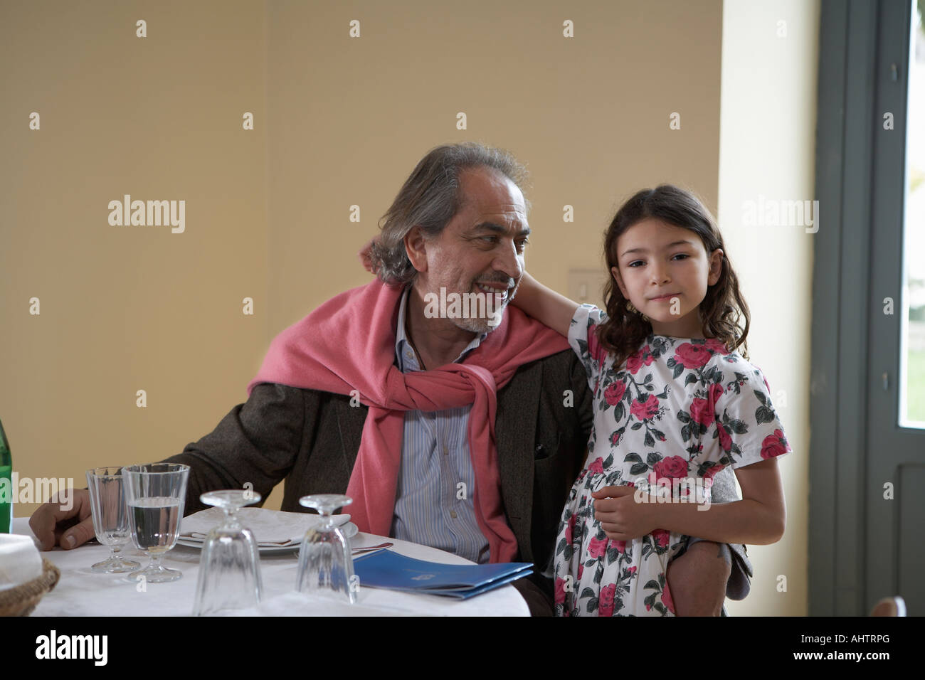 La ragazza (5-7) seduta con il nonno in una tabella Foto Stock