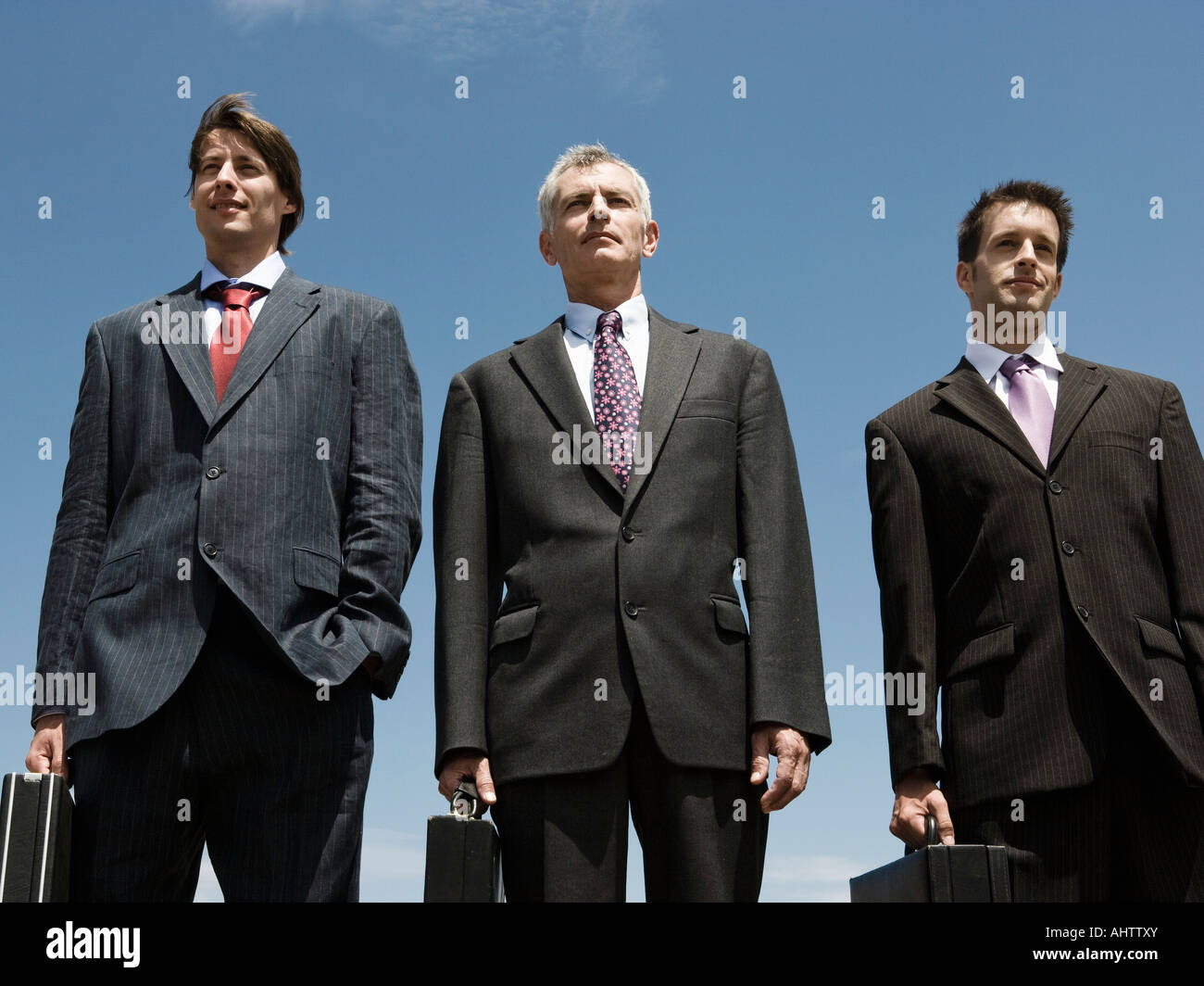 Tre uomini di affari in piedi a fianco a fianco. Foto Stock