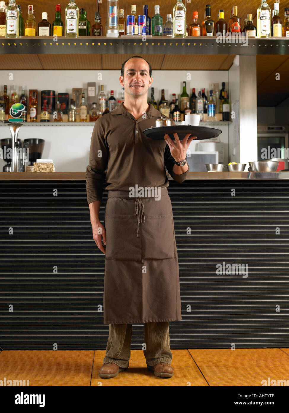 Cameriere nel lungo grembiule tenendo il vassoio nella parte anteriore del  bar Foto stock - Alamy