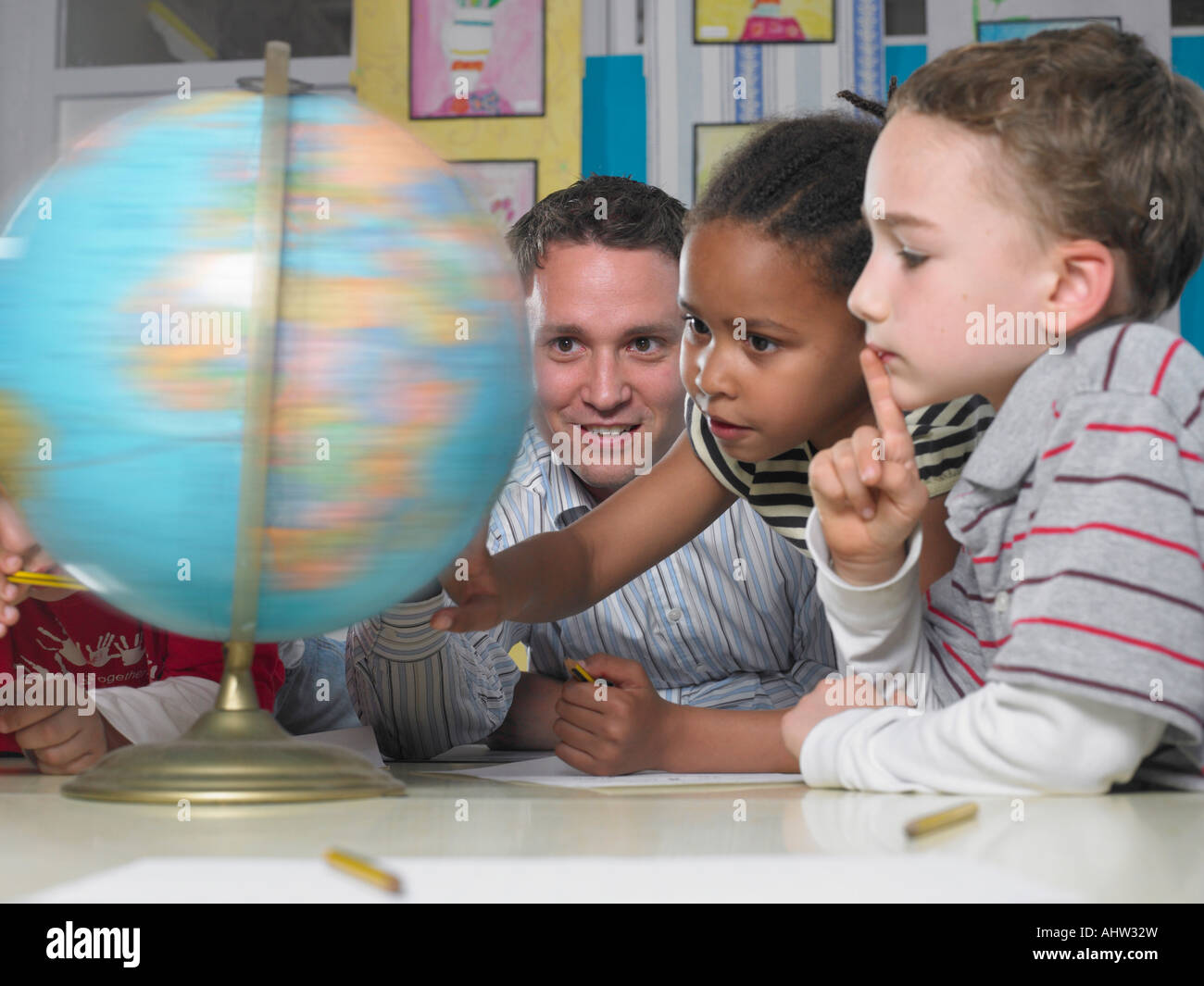 Insegnante maschio guardando il mondo che gira con un ragazzo e una ragazza Foto Stock