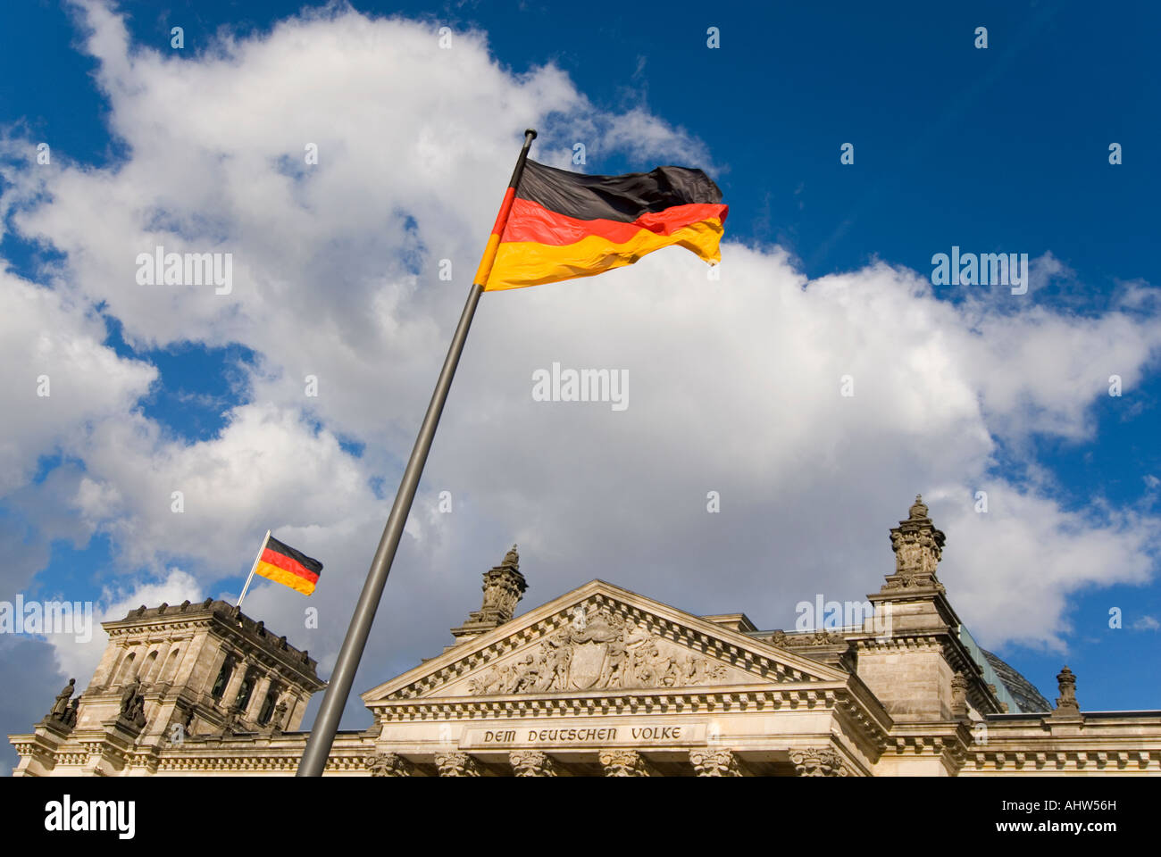 Orizzontale vista anteriore del Reichstag con la famosa iscrizione "em Deutschen Volke', e un enorme bandiera tedesca in una giornata di sole Foto Stock