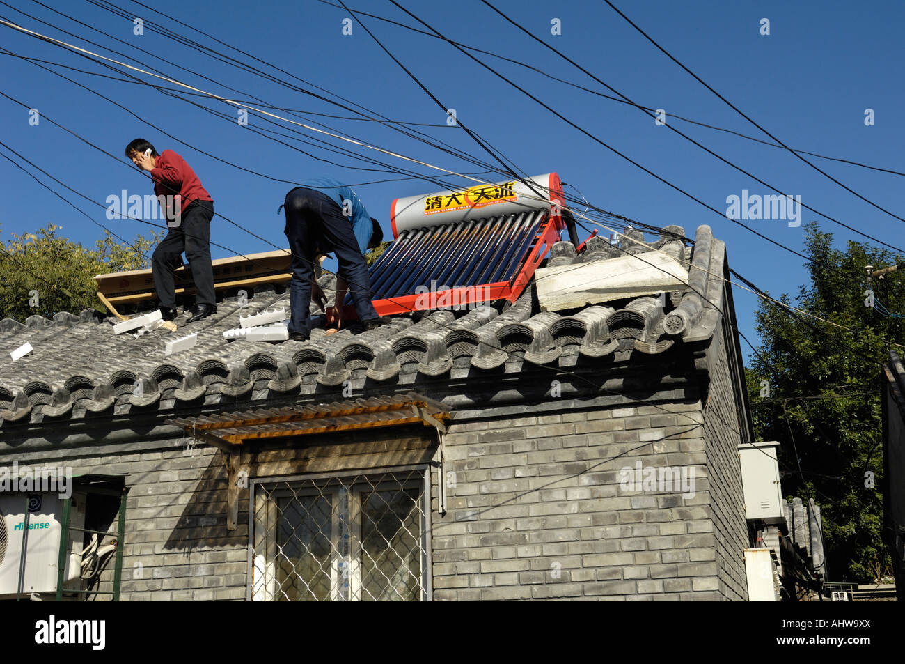 Un uomo installa energia solare powered riscaldatore di acqua calda Serbatoio sul tetto di casa nel centro di Pechino , Cina. 14 Ott 2007 Foto Stock