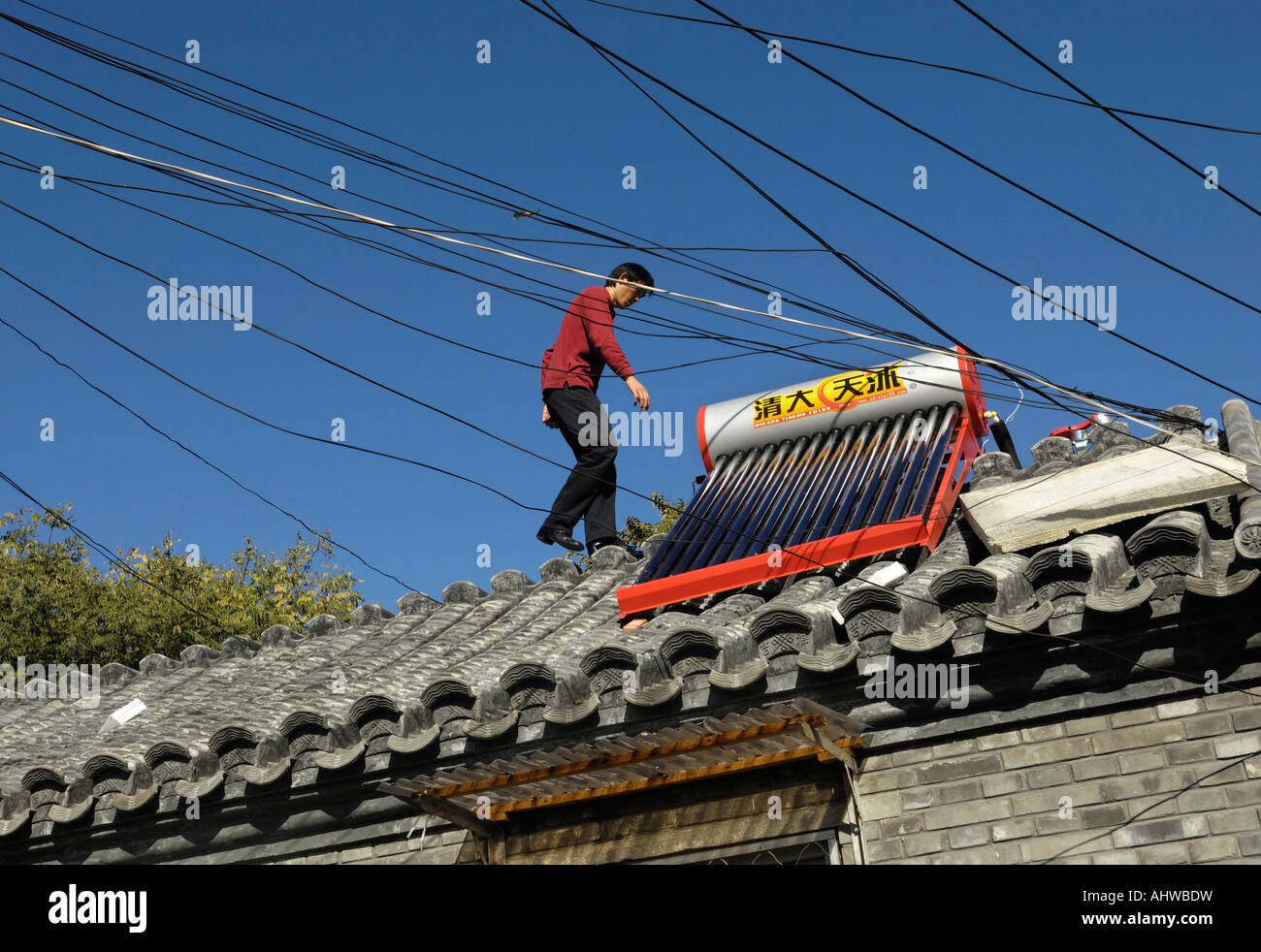 Un uomo installa energia solare powered riscaldatore di acqua calda Serbatoio sul tetto di casa nel centro di Pechino , Cina. 14 Ott 2007 Foto Stock