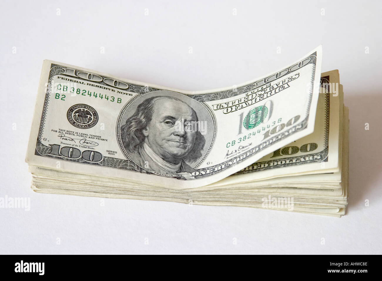 Pila di banconote da cento dollari in valuta statunitense sul tavolo bianco Foto Stock