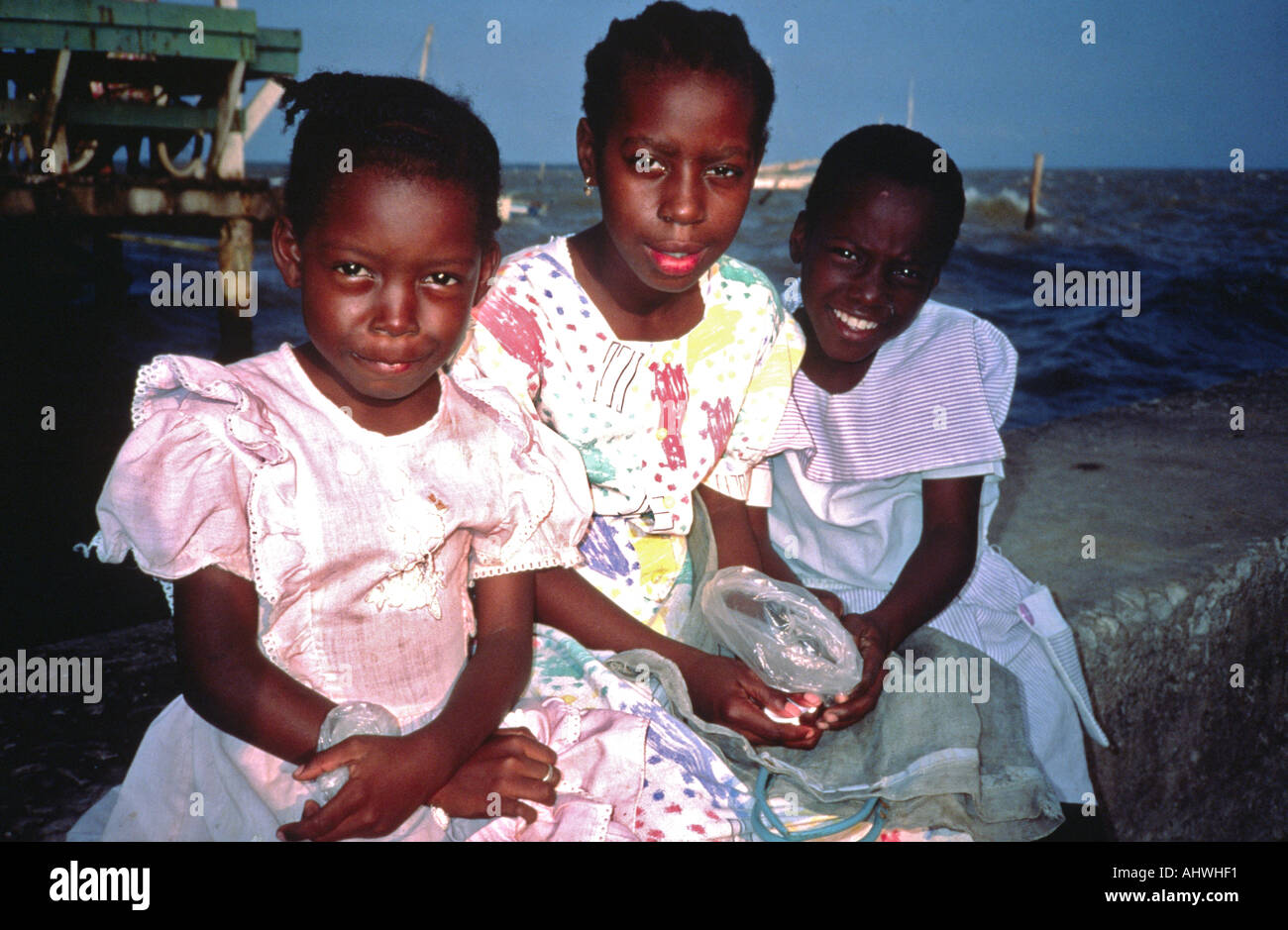 Ritratto di tre sorelle seduti in riva al mare, Città del Belize, Belize Foto Stock