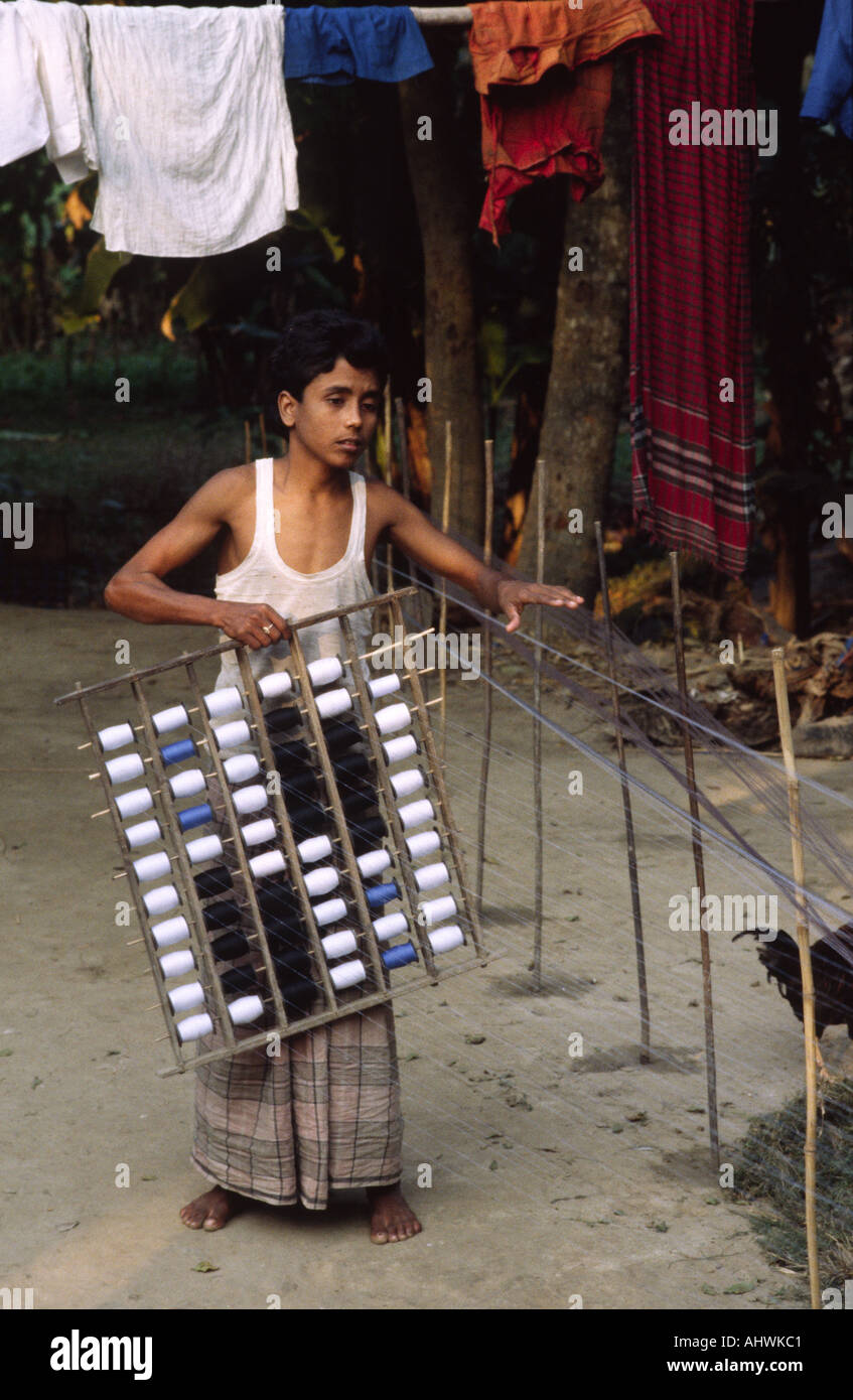 Tessitore giovane che prepara thetrama per un telaio fatto a mano in un piccolo laboratorio rurale. Bangladesh Foto Stock