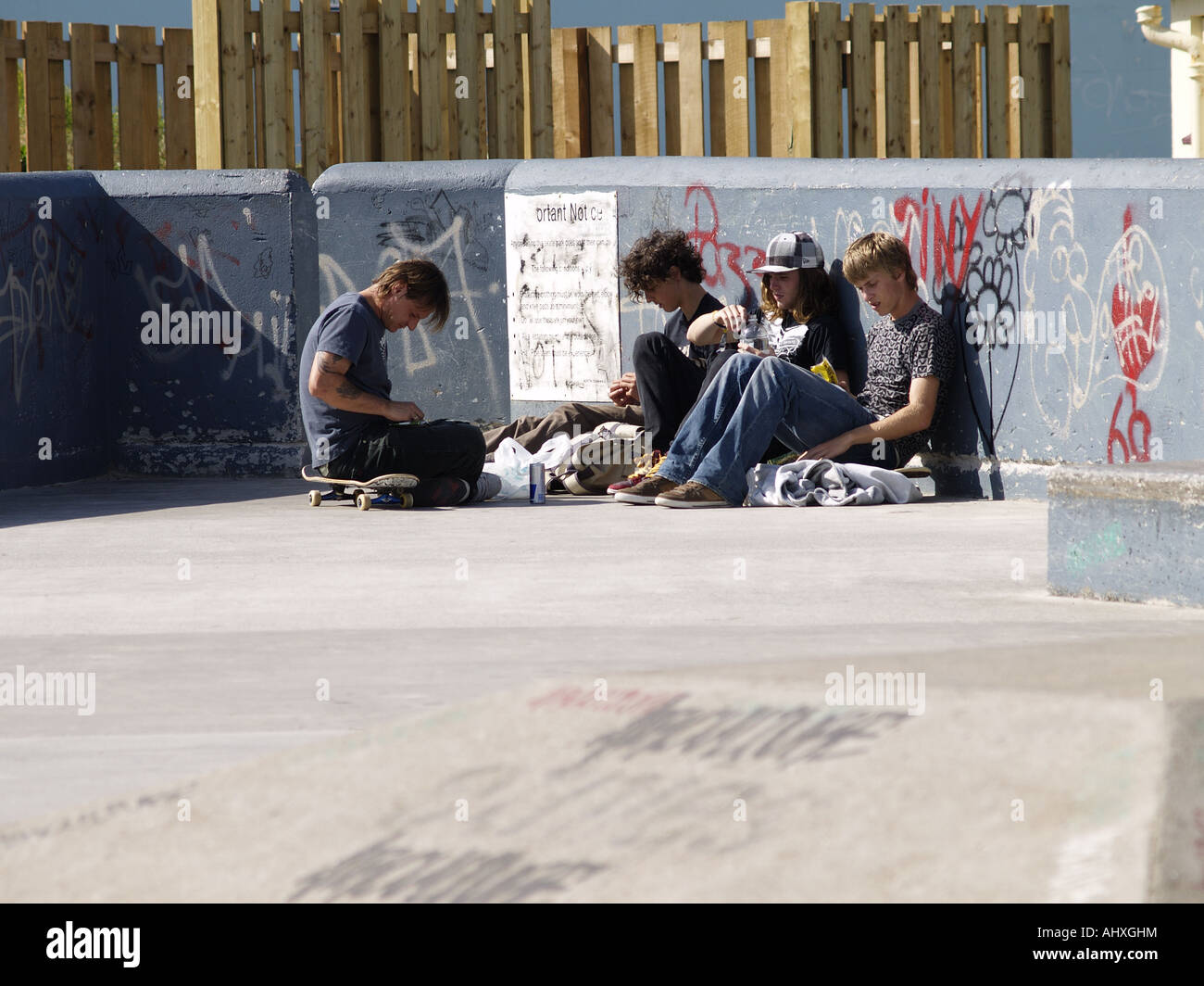 Quattro adolescenti maschi seduti insieme in un skate park Foto Stock
