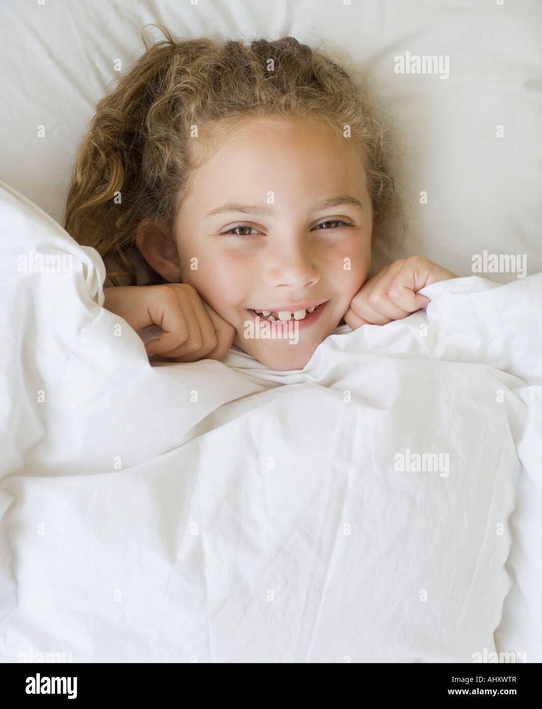 Ragazza tirando una coperta fino al mento Foto Stock