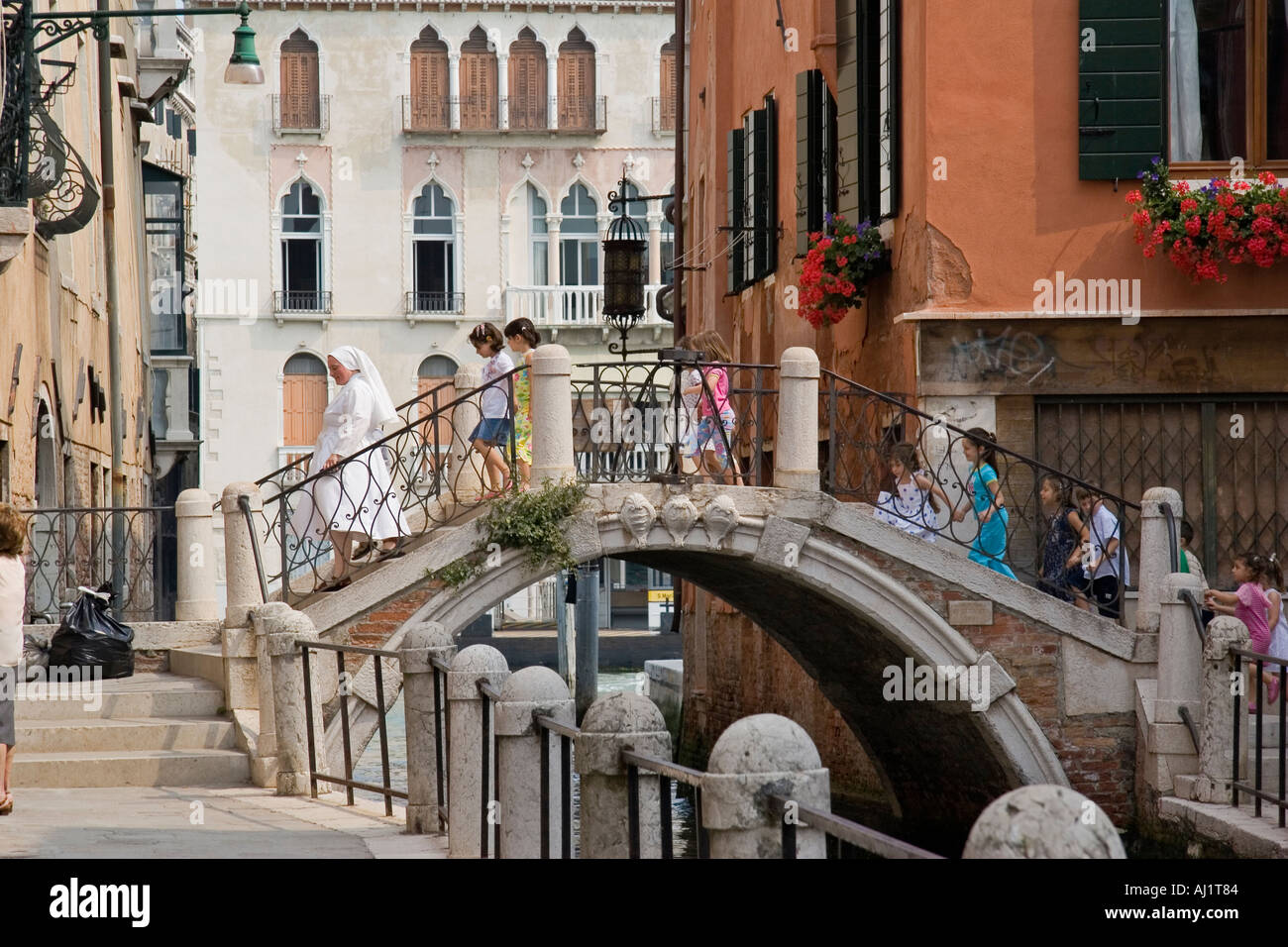 Coppie di scuola bambini holding hands seguire nun indossando abito bianco su un ponte sul canal sestiere di Dorsoduro di Venezia Foto Stock