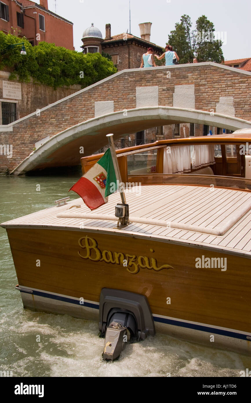 Bandiera Italiana vola da poppa di entrobordo fuoribordo taxi d'acqua vicino al ponte sul Canal Venezia Italia Foto Stock