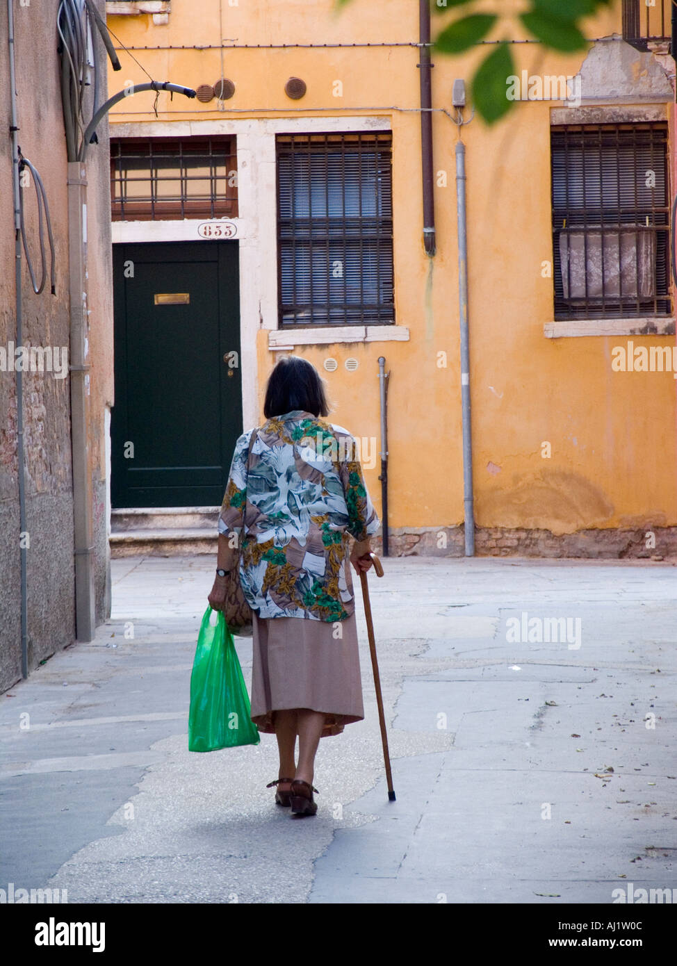 Vecchia donna con canna camminando per strada nel quartiere di Dorsoduro di Venezia Italia Foto Stock