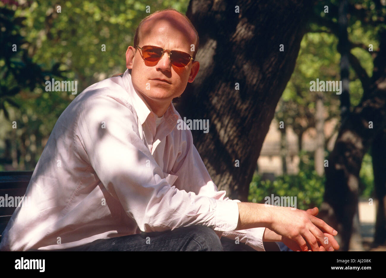 Uomo seduto una panchina nel parco di sole Foto Stock