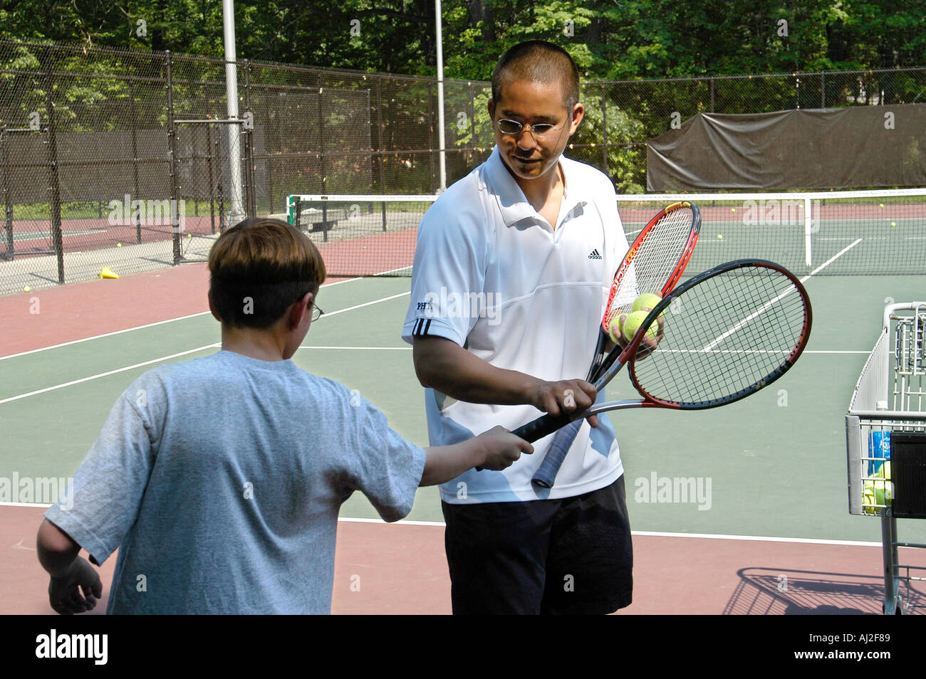 I ragazzi imparano a giocare a tennis presso il pubblico corte di ricreazione Foto Stock
