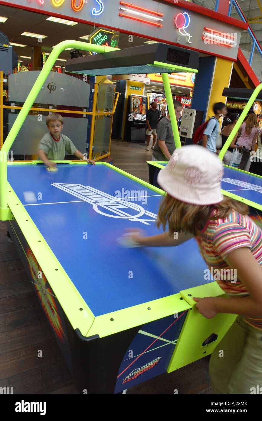 Bambini che giocano air hockey gioco all'interno di seaside amusements fiera arcade Foto Stock