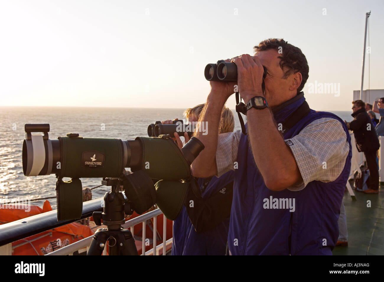 Primo piano di un uomo e di una donna a guardare il mare con un binocolo dalla nave Foto Stock
