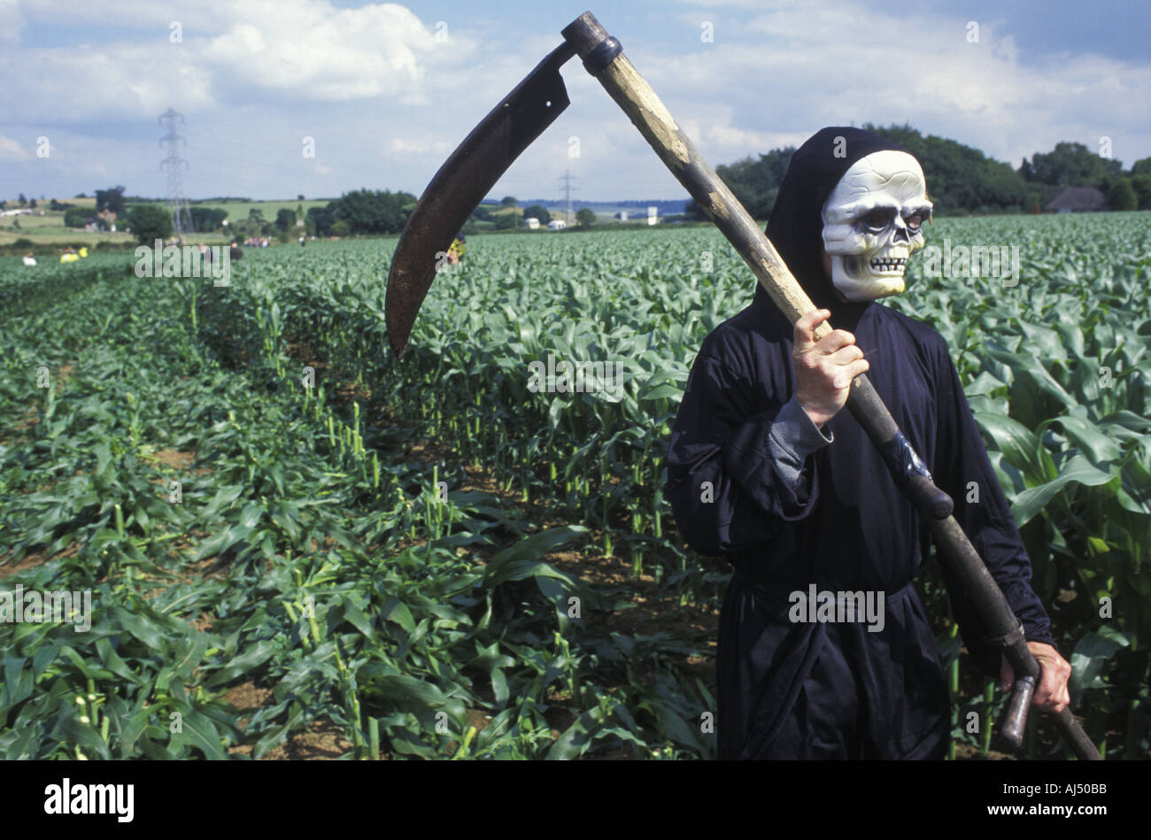 Un anti GM protester vestito come Grim Reaper fa il suo modo di un campo per abbattere il mais GM Foto Stock