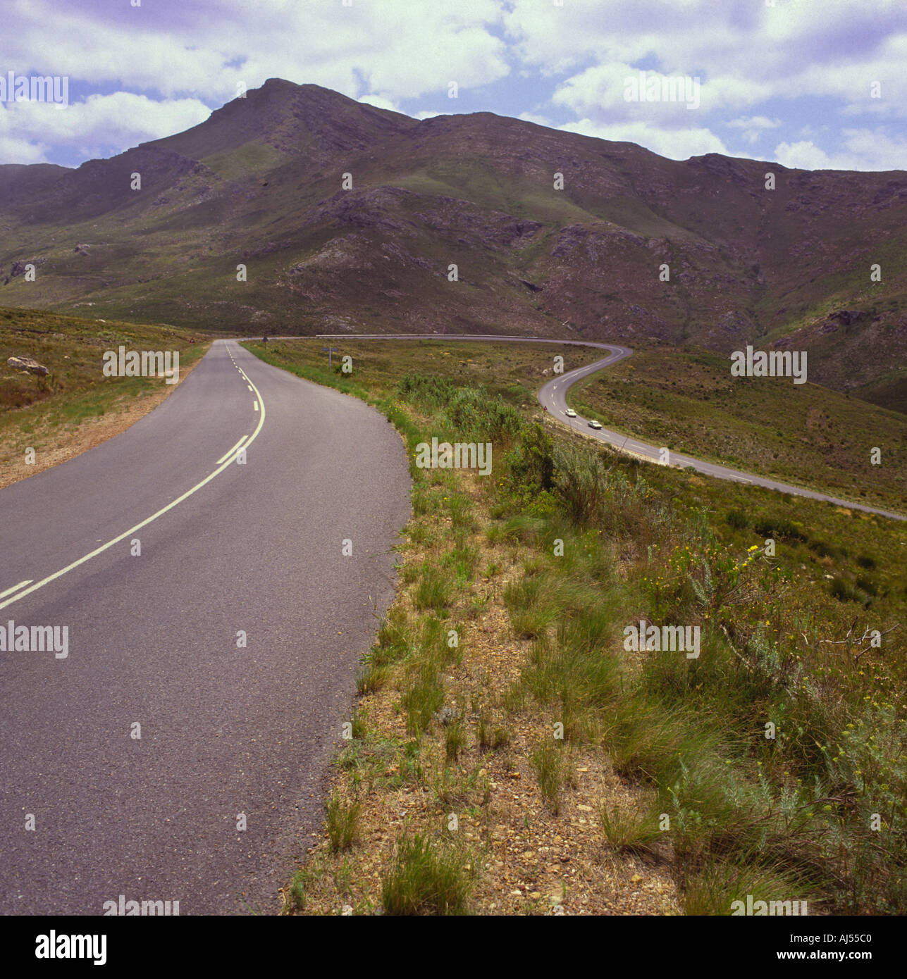 Due vetture rendendo il loro cammino lungo ed attorno ad una curvatura del tratto di strada e colline Franschhoek Pass Provincia del Capo Sud Africa Foto Stock