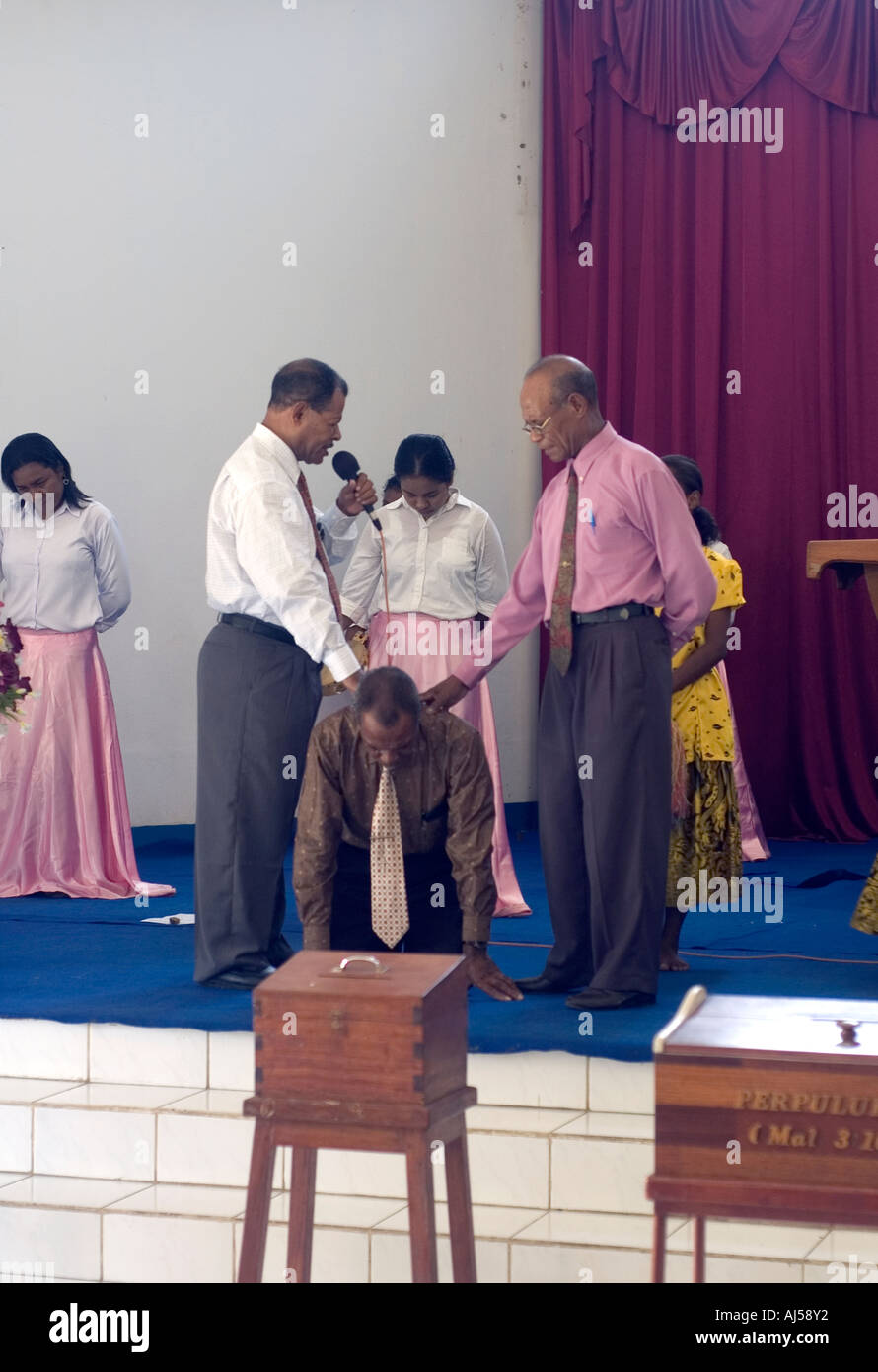 Una politica di Papua e dignitario religioso facendo una speciale 'fortuna' preghiera per l'uomo in ginocchio, Jayapura Foto Stock