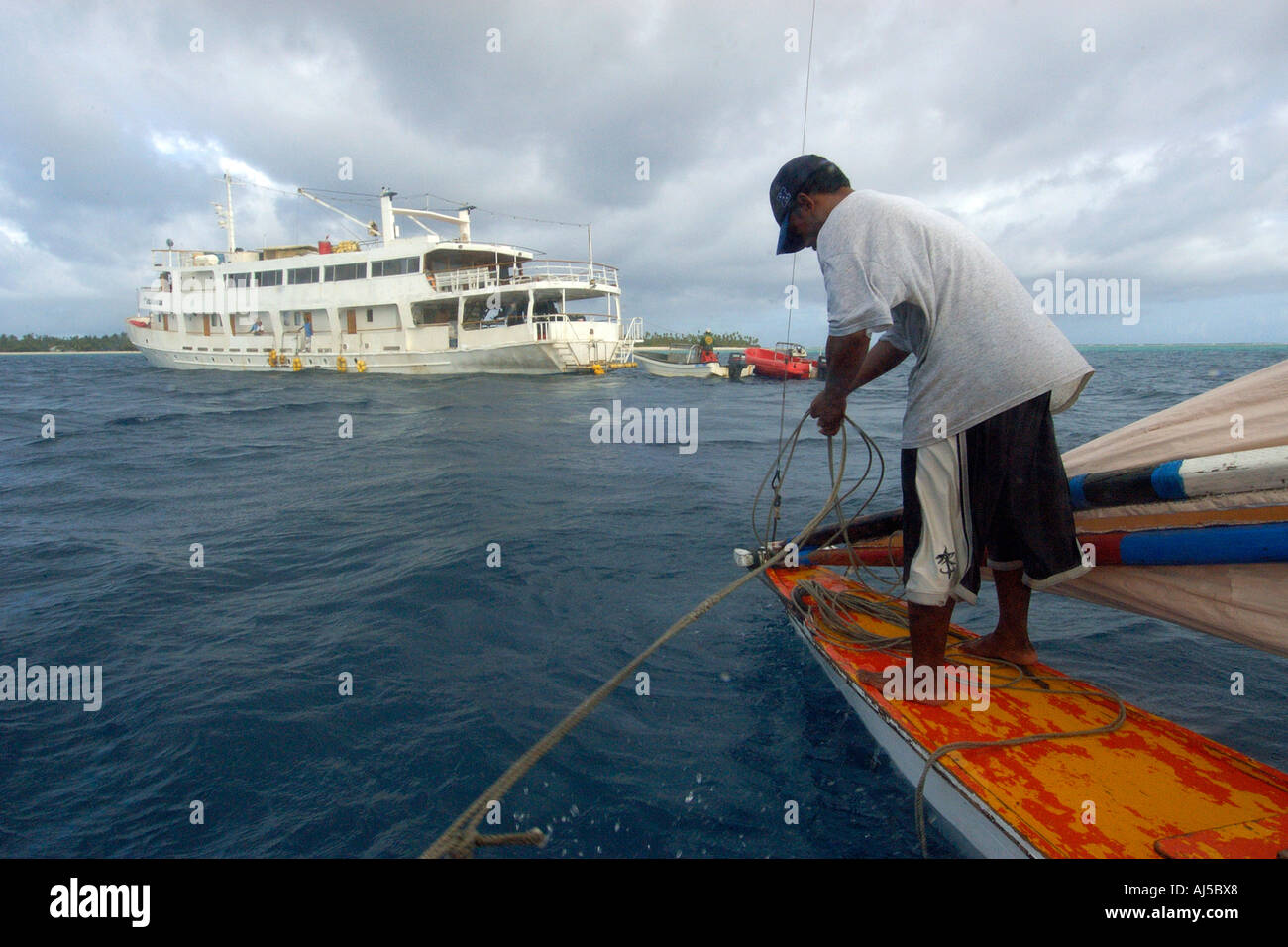 Marshalhese uomo vela di commutazione della posizione in una tradizionale canoa outrigger Ailuk atollo delle Isole Marshall del Pacifico Foto Stock