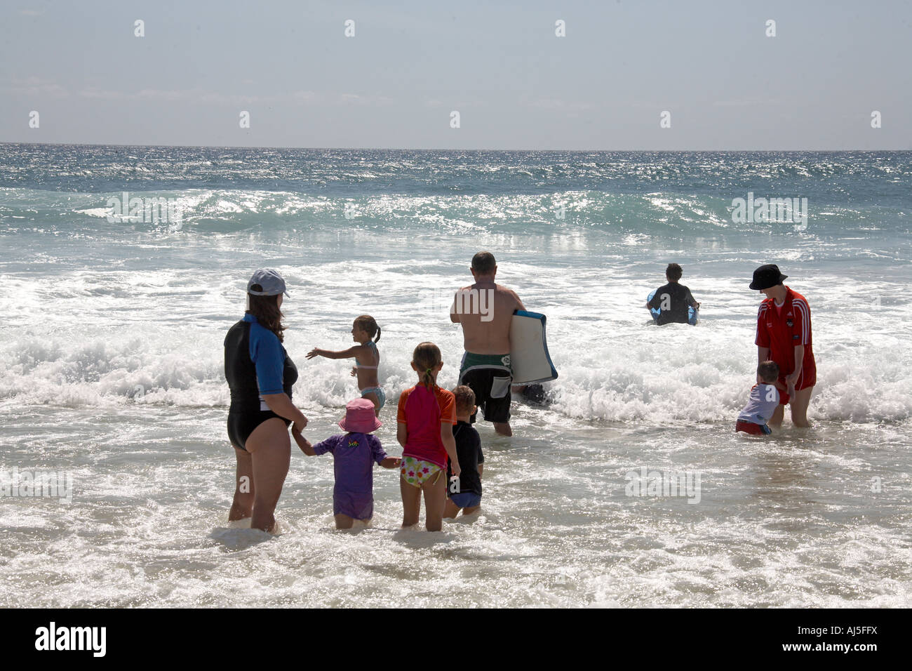 Le persone e le famiglie in piedi in mare in attesa di fare surf e guardando le onde in Surfers Paradise Queensland QLD Australia Foto Stock