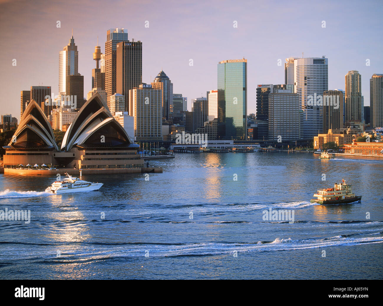 Barca taxi attraversando il Porto di Sydney con la Opera House e lo skyline all'alba Foto Stock