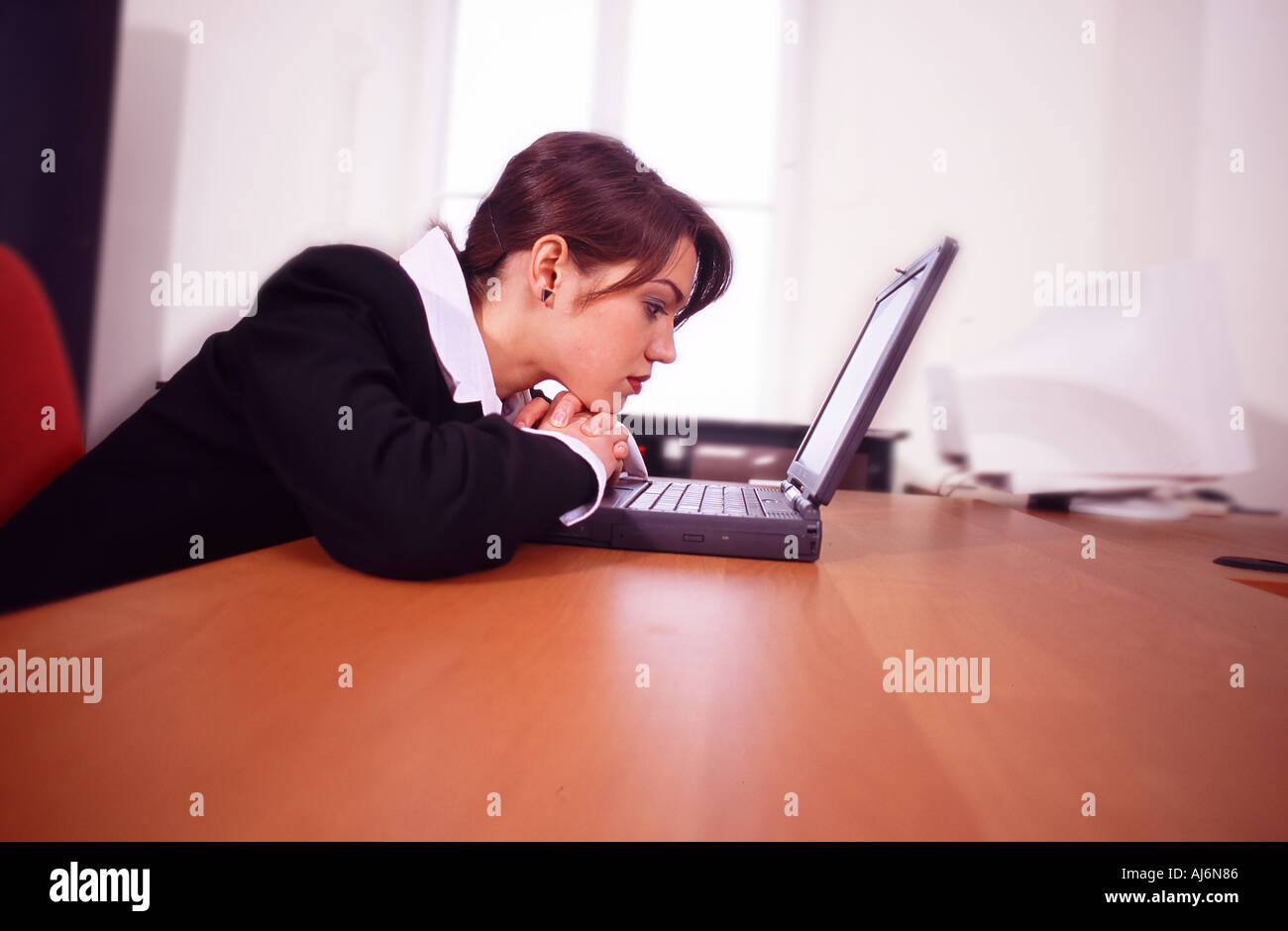 Donna seduta alla scrivania e utilizzando un computer portatile. Foto Stock