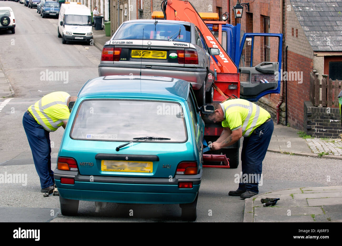 DVLA appaltatori supportati da funzionari di polizia take away permessi non tassati automobili parcheggiate sulla autostrada nel South Wales UK GB Foto Stock