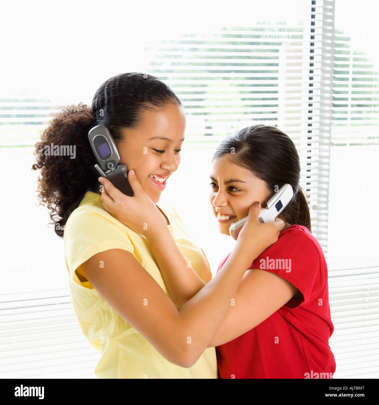 Due ragazze preteen azienda telefoni cellulari fino a ogni altro orecchie Foto Stock