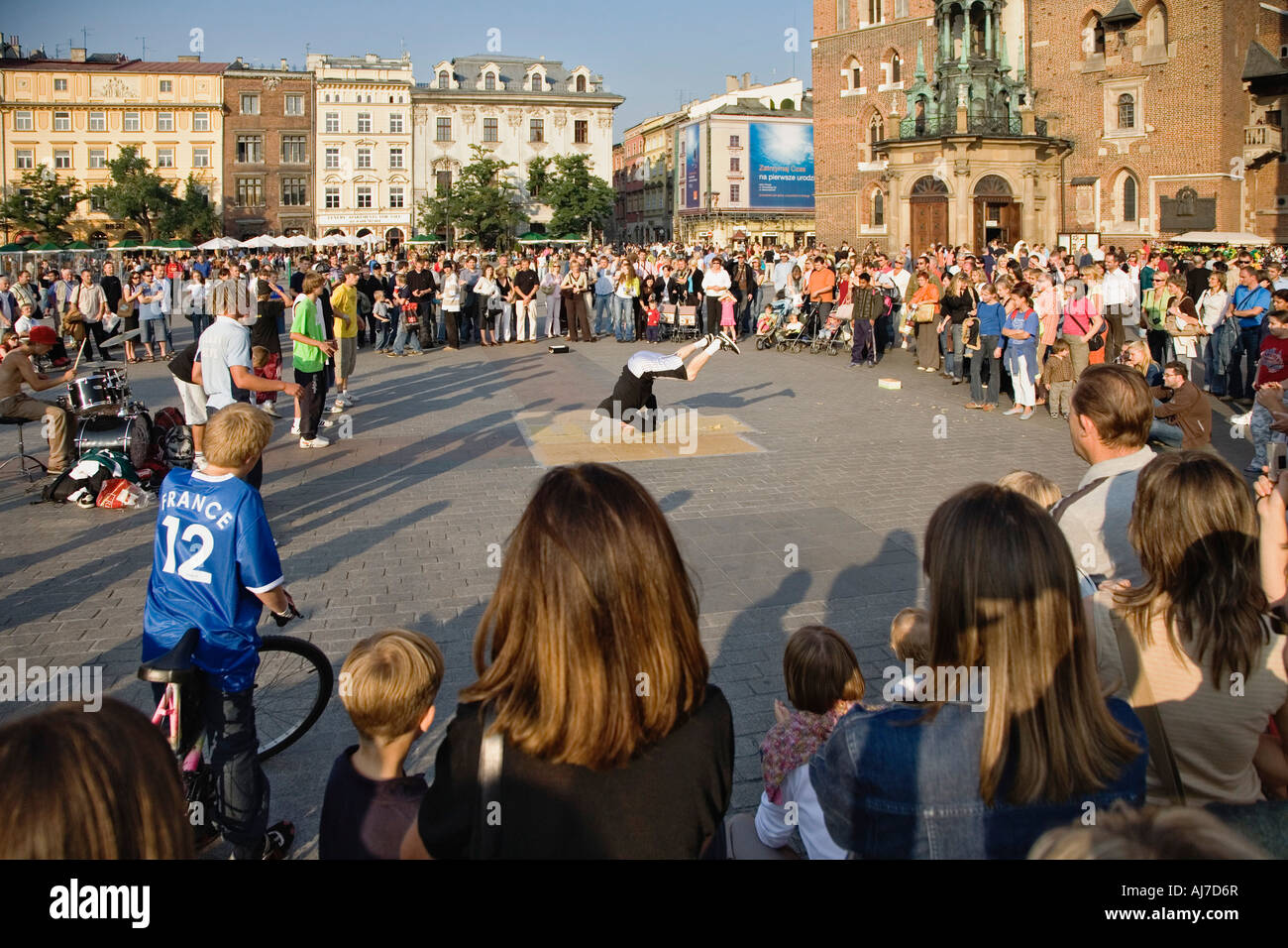 Tourist si riuniscono per guardare gli artisti di strada vicino alla chiesa di Santa Maria in Piazza del Mercato nel centro storico di Cracovia, in Polonia. Foto Stock