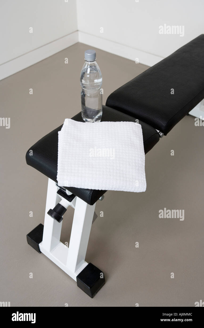 Panca pesi con una bottiglia d'acqua e asciugamani Foto Stock