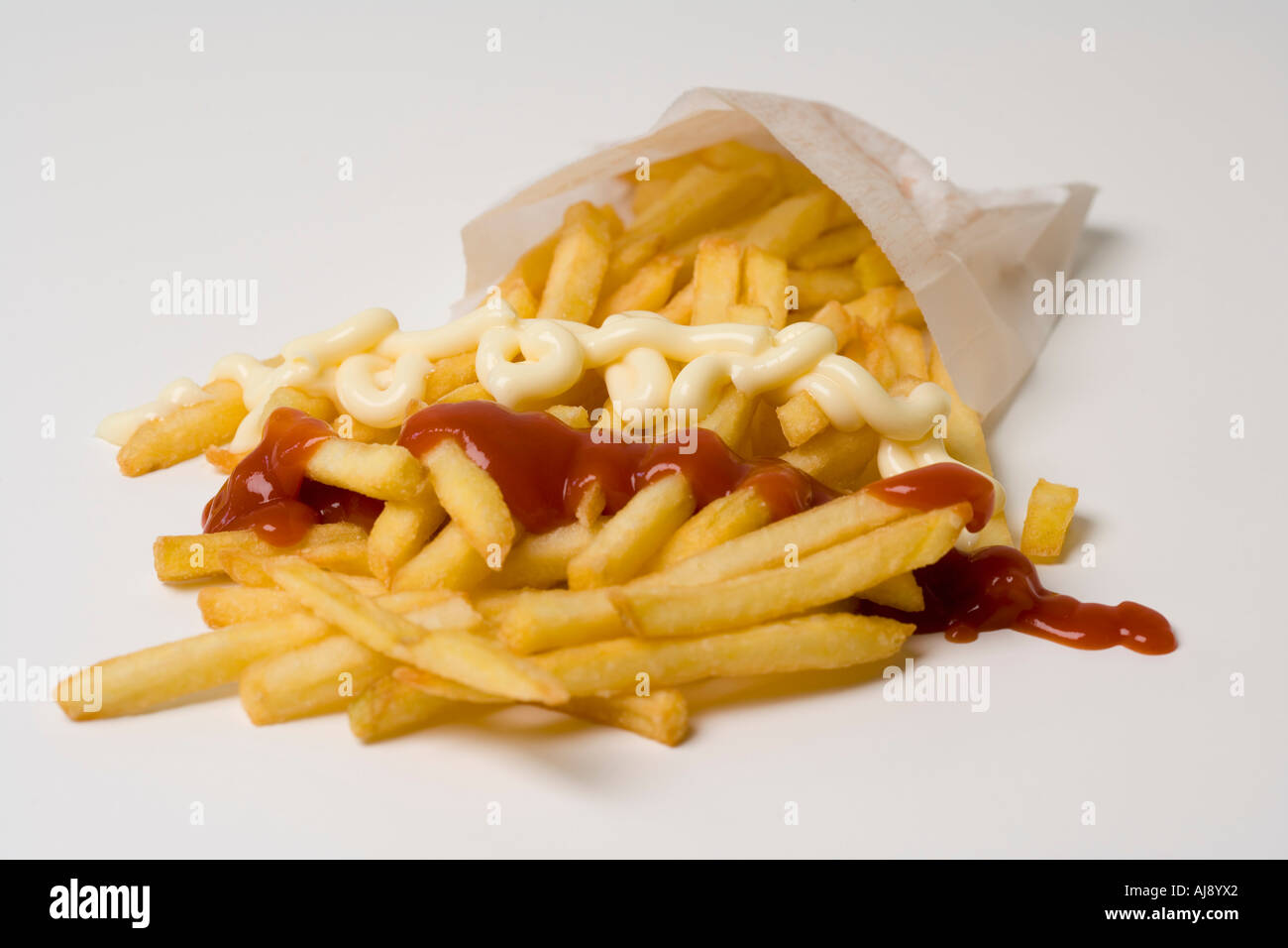 Patate fritte con ketchup e maionese in un sacchetto di carta Foto Stock