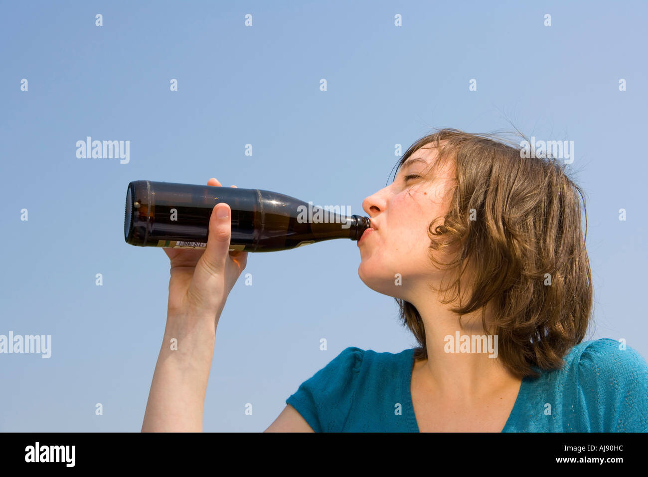 Giovane donna di bere da una bottiglia di birra Foto Stock