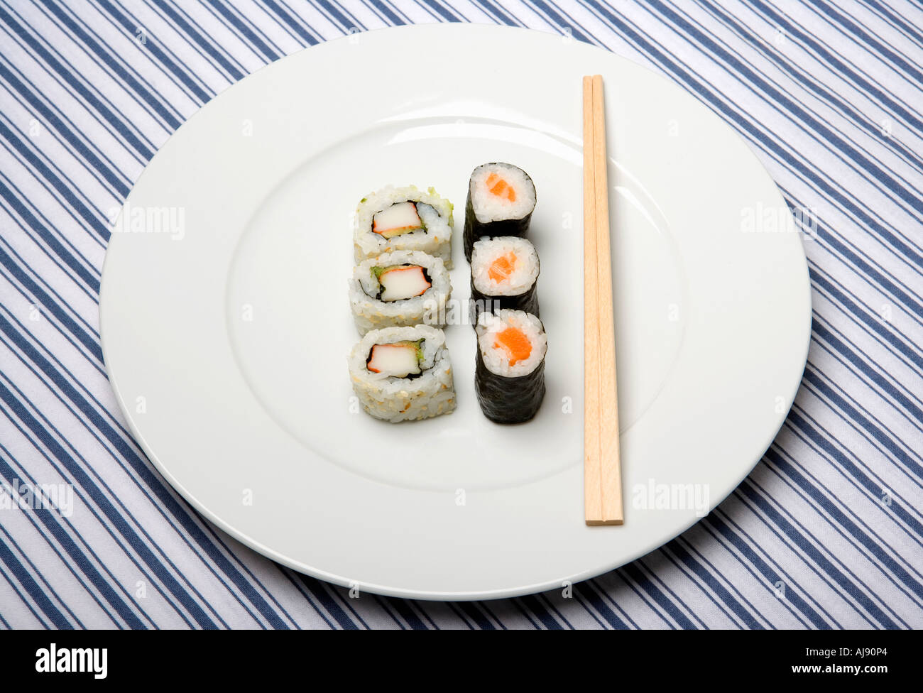 Piastra con un assortimento di sushi e bacchette di legno Foto Stock