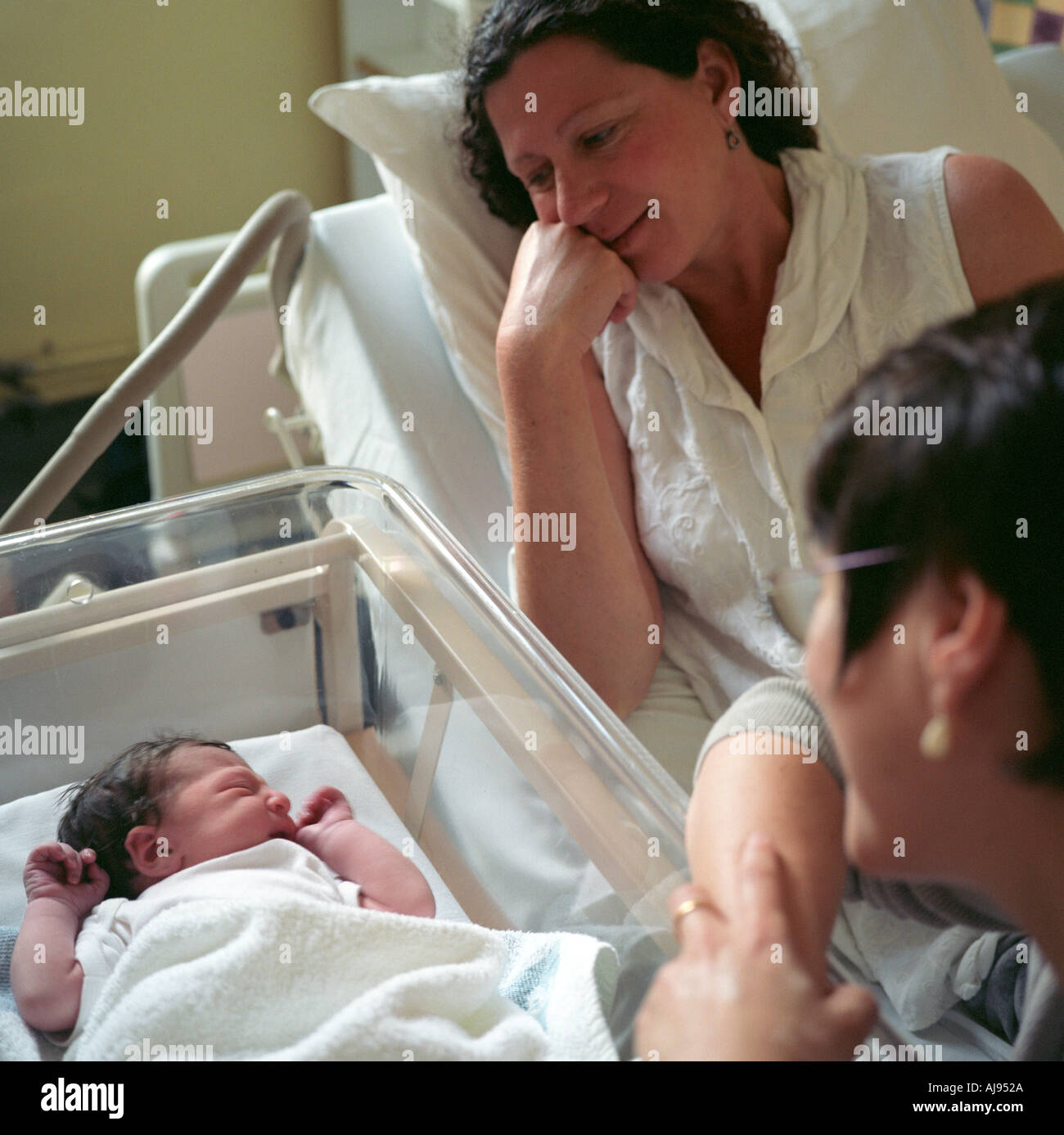 Un neonato di tre ore di vecchio guardato da sua madre e la sua amica in ospedale, University College Hospital di Londra Foto Stock
