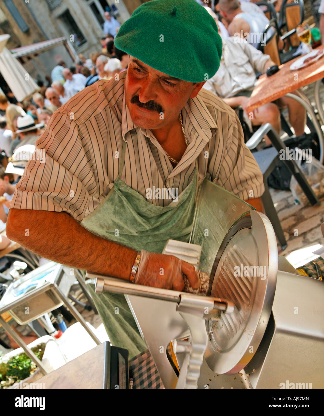 Il francese in berretto verde per affettare prodotti locali prosciutto Street Market Saint Antonin Toulouse Francia Foto Stock