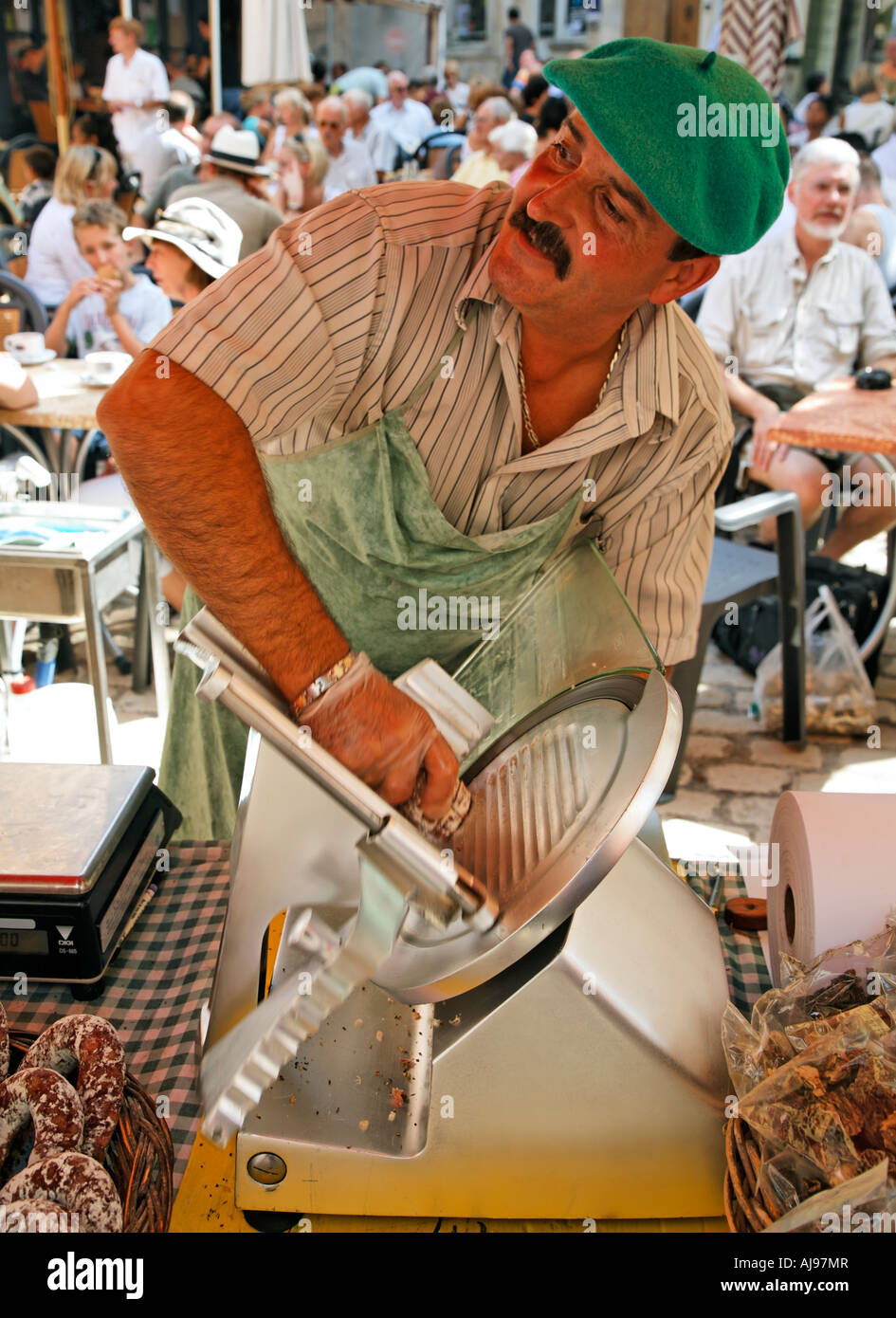 Il francese in berretto verde per affettare prodotti locali prosciutto Street Market Saint Antonin Toulouse Francia Foto Stock