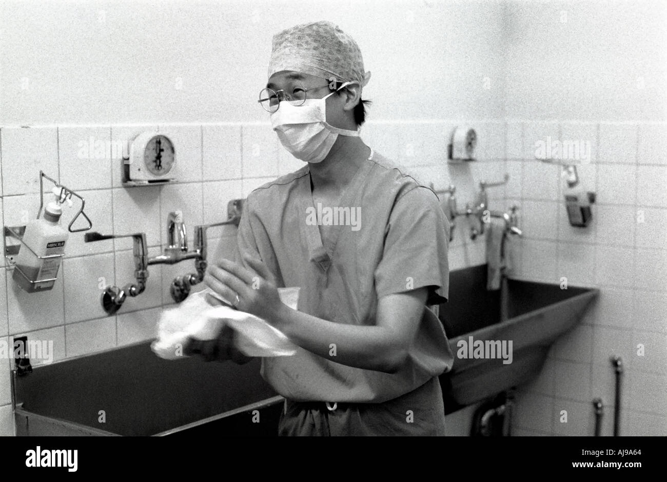 Un anglo-cinese medico junior il lavaggio fino dopo un funzionamento a Whipps Cross Hospital di Londra, Regno Unito. Foto Stock