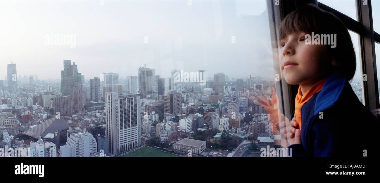 Un ragazzo che guarda fuori sopra la skyline di Tokyo Foto Stock