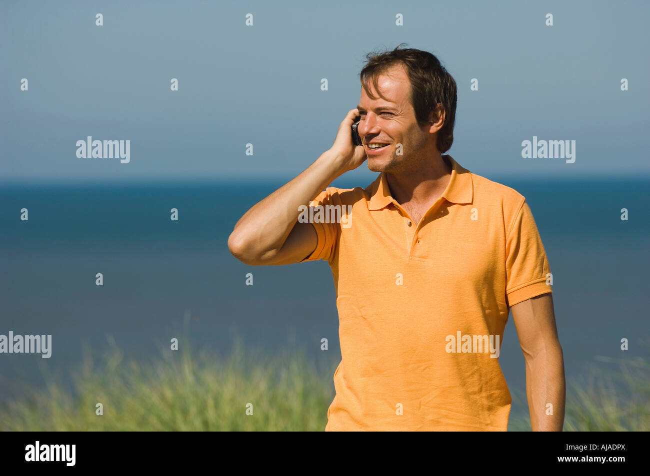 L'uomo talknig sul telefono cellulare sulla spiaggia Foto Stock