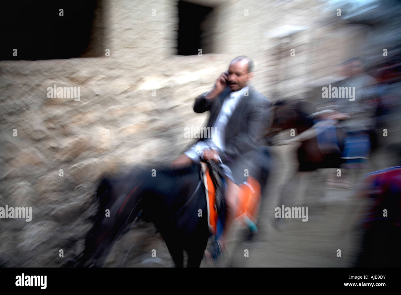 Uomo a cavallo di effettuare una chiamata su un telefono mobile con motion blur Cairo Egitto Africa Foto Stock