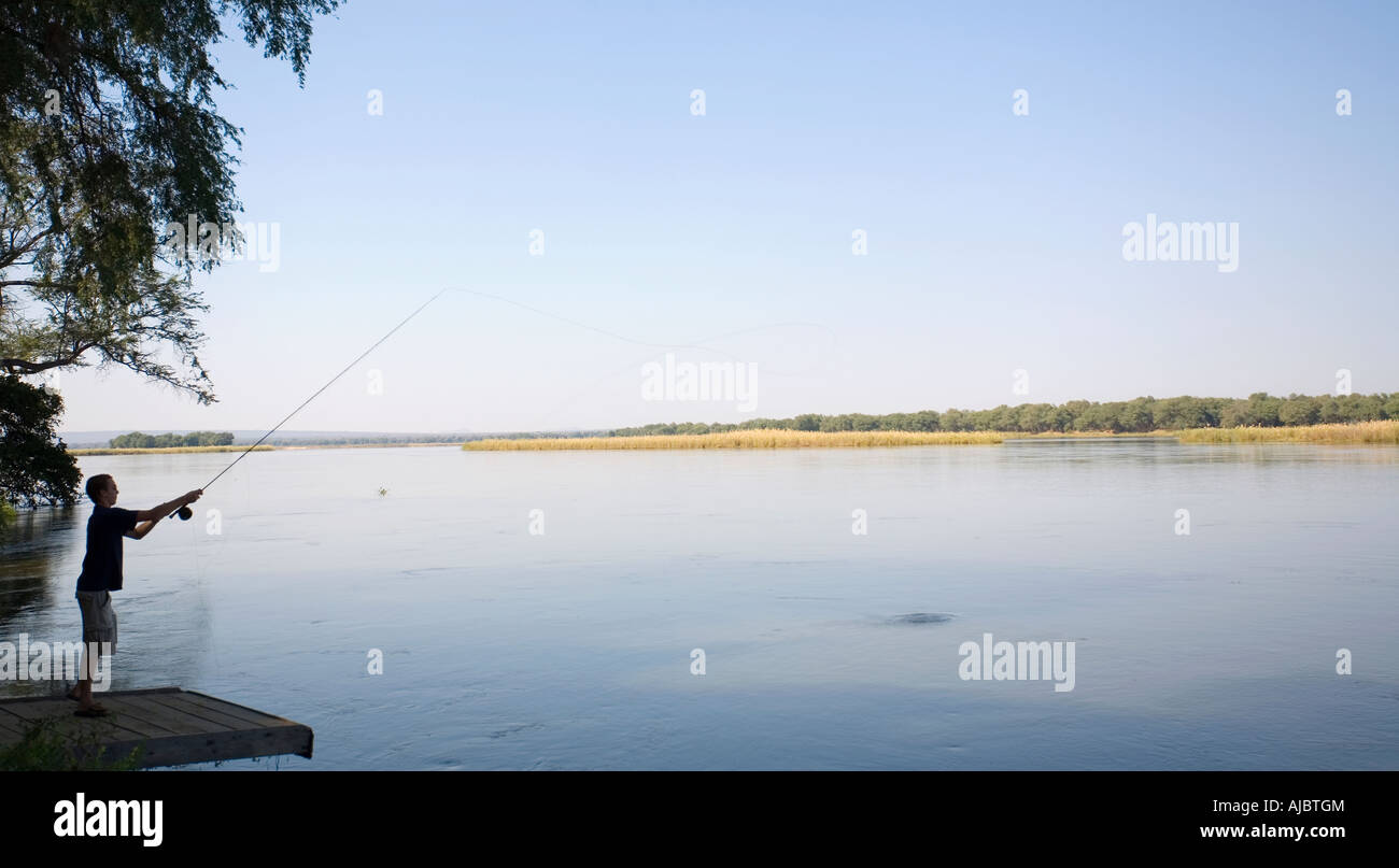 Giovane uomo la pesca in fiume Zambezi - Vista laterale Foto Stock