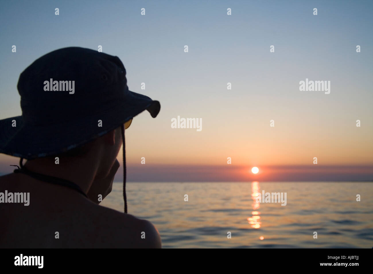 Silhouette di un giovane uomo di godersi il tramonto Foto Stock