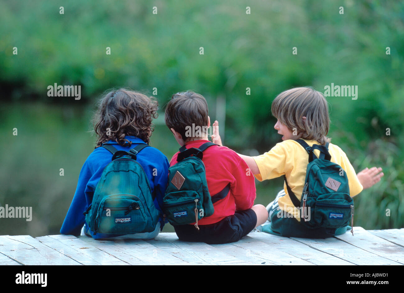 Tre ragazzi sul pontile, vista posteriore, portando zaini Foto Stock