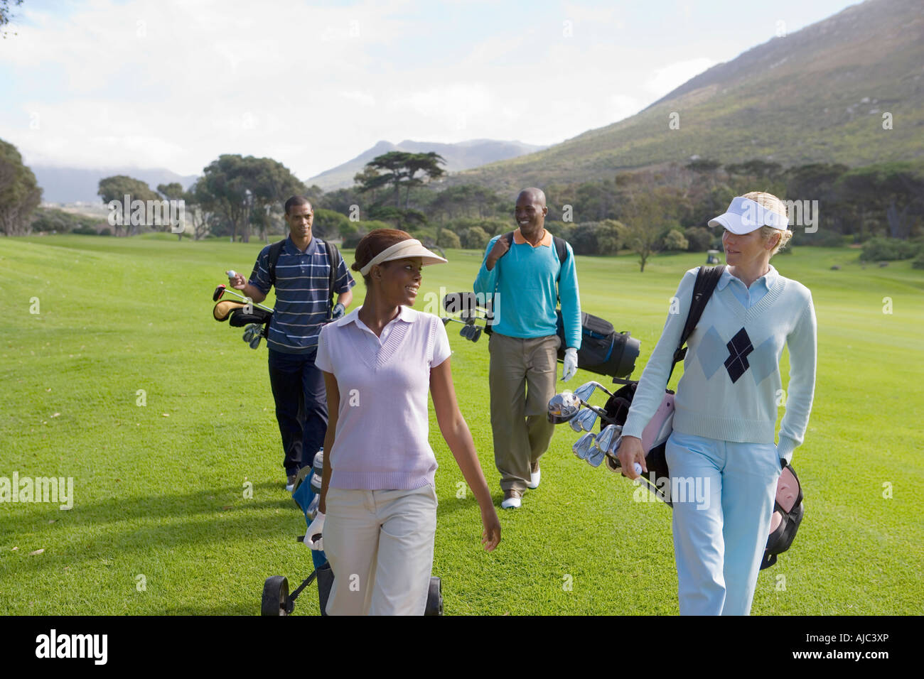 I golfisti camminando giù Fairway parlando Foto Stock