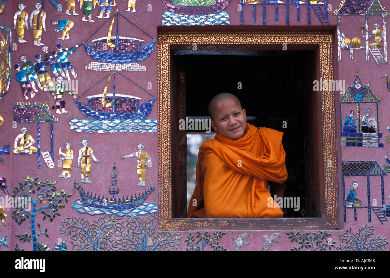 Monaco novizio nella finestra del mosaico decorato tempio di Wat Xieng Thong Luang Prabang s più famoso monastero Laos Foto Stock
