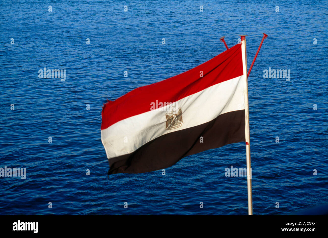 Luxor Egitto Bandiera egiziana con emblema nazionale l'aquila egiziana di Saladin & fiume Nilo Foto Stock