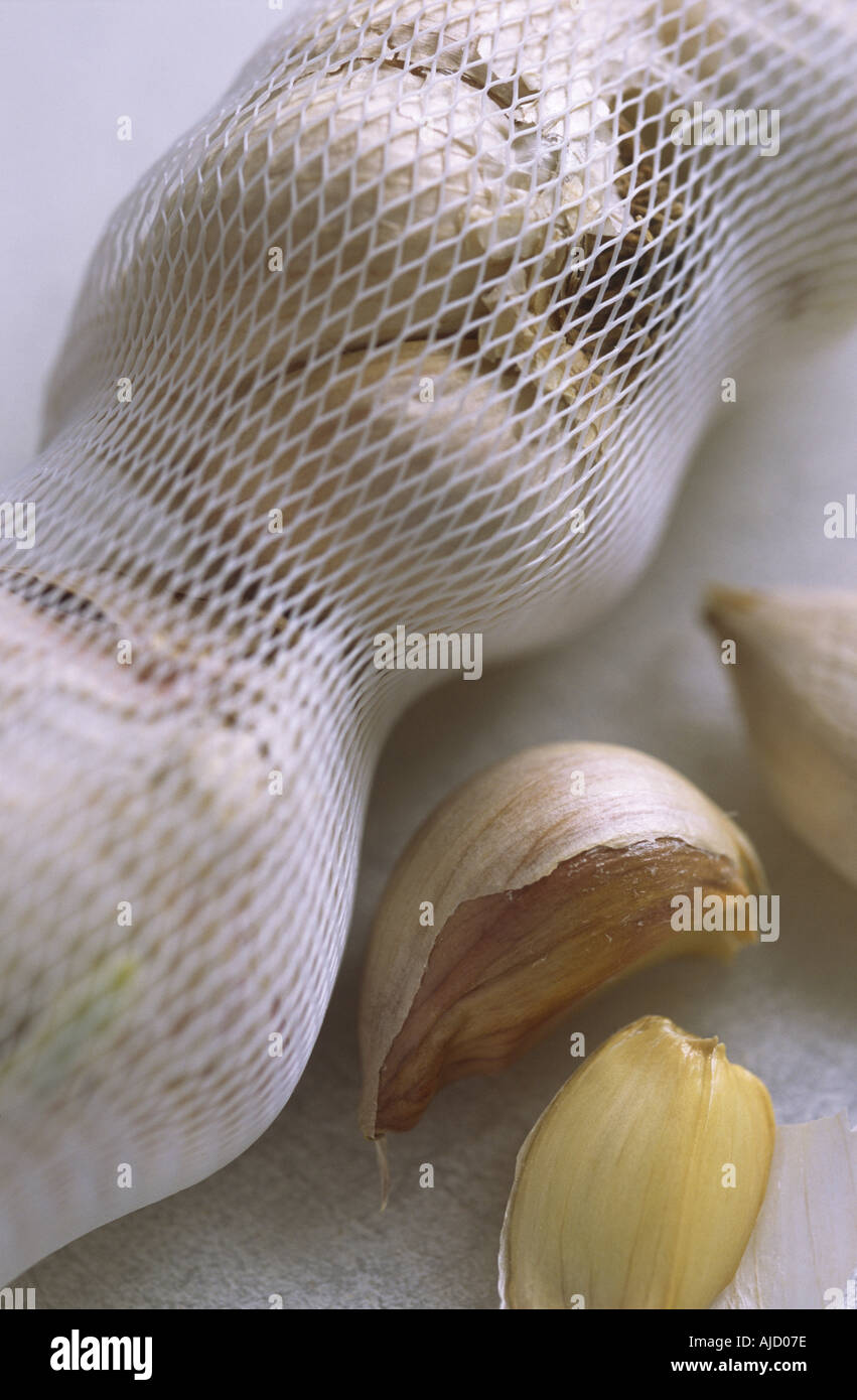Spicchio di rete con bulbi d'aglio e qualche spicchio su un tagliere. Foto Stock