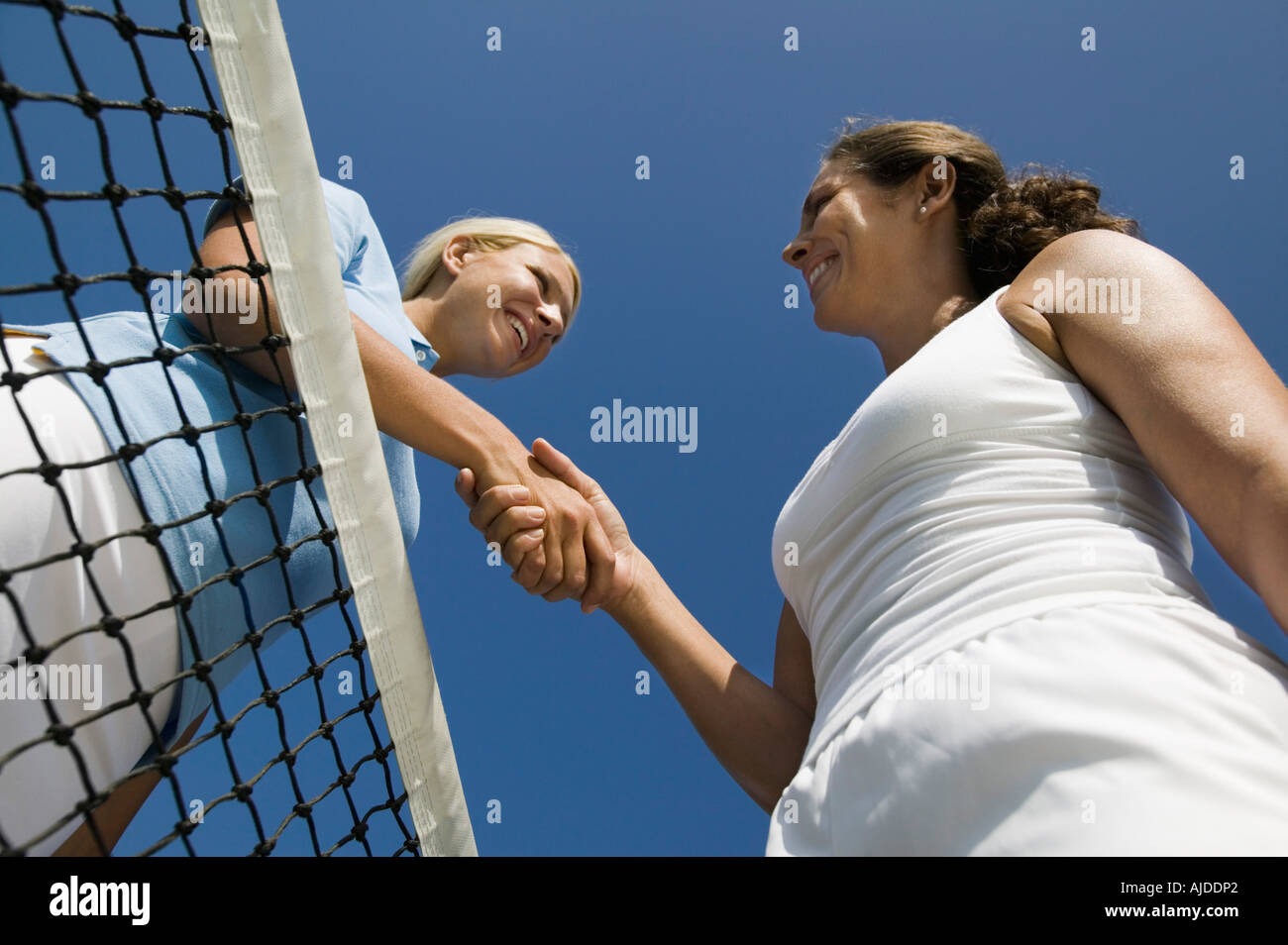 Due femmina i giocatori di Tennis agitando la mano su campo da tennis net, basso angolo di visione Foto Stock