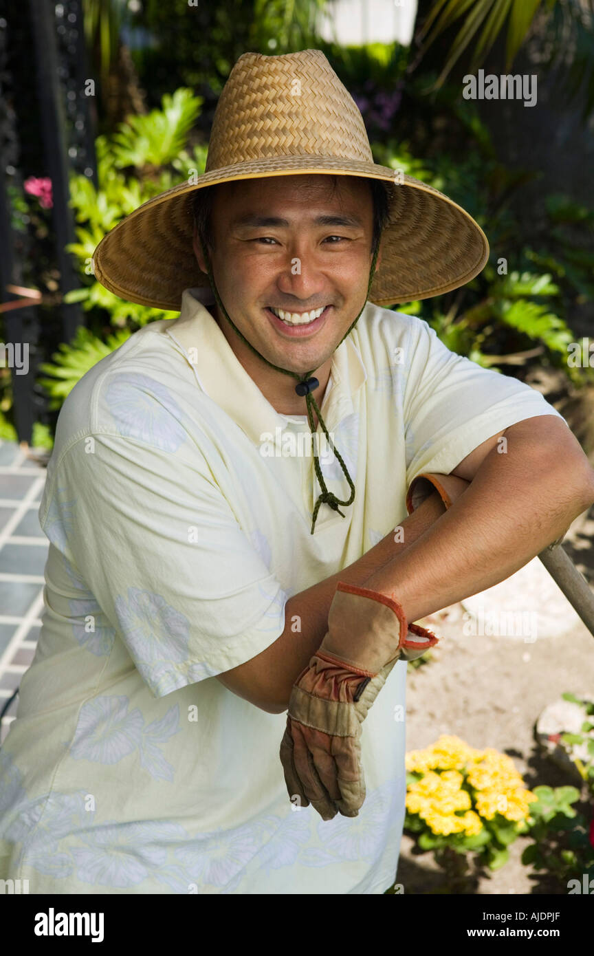 Uomo che indossa cappello di paglia in giardino, (verticale). Foto Stock