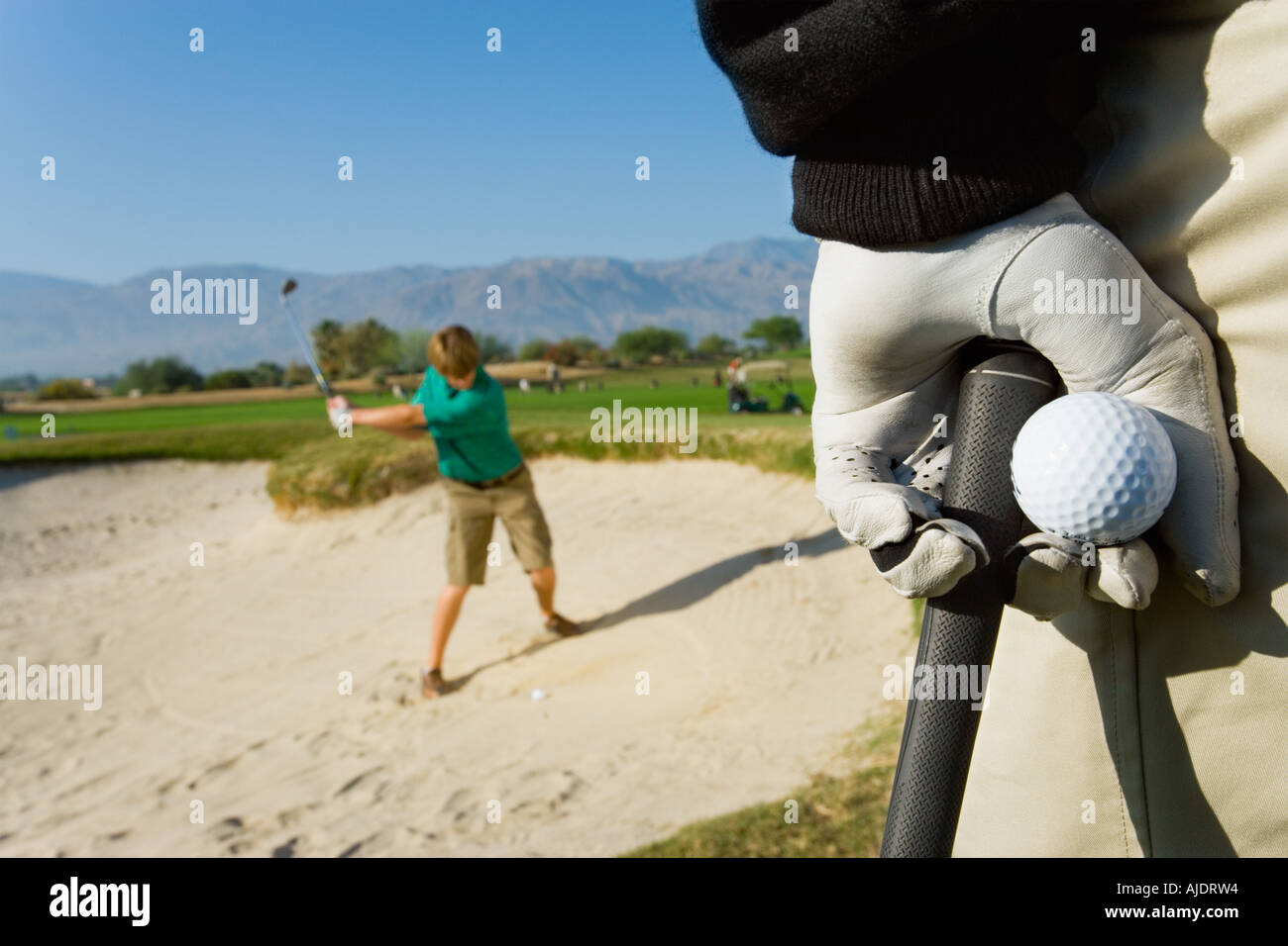Il Golfer guardare altri golfista colpire la sfera dalla trappola di sabbia Foto Stock